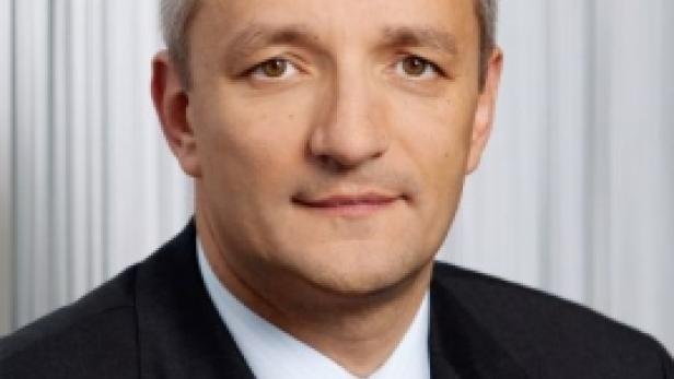 Ein Mann mit Anzug und Krawatte blickt in die Kamera.