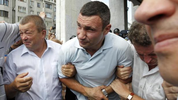 Vitali Klitschko wird von mehreren Personen umringt und festgehalten.