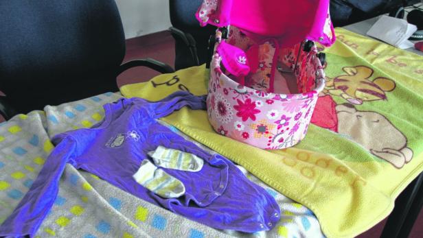 Das Baby trug einen lila Strampler und Streifen-Söckchen.