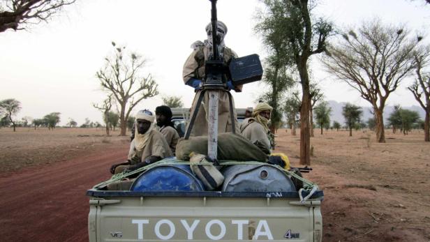 Bewaffnete Männer fahren auf der Ladefläche eines Toyota-Pickups durch eine trockene Landschaft.