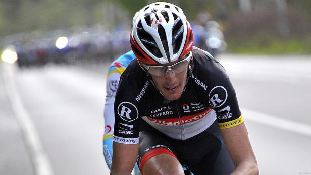 Ein Radrennfahrer während eines Rennens mit anderen Fahrern im Hintergrund.