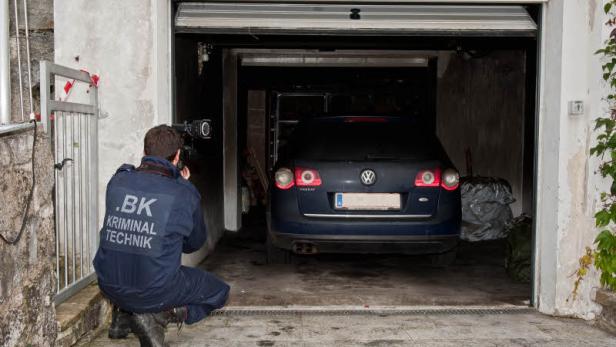 Ein Kriminaltechniker fotografiert ein Auto in einer Garage.