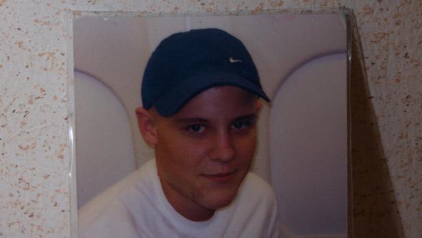 Ein junger Mann mit kurzer Frisur und blauem Basecap lächelt.