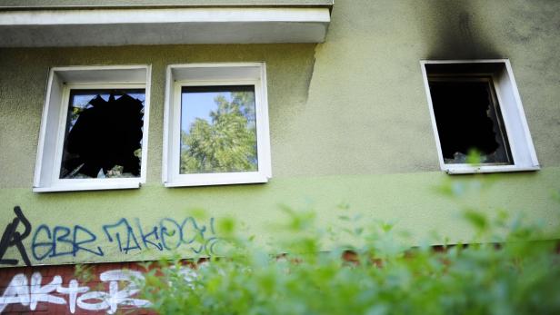 Die Fassade eines Hauses mit Graffiti und zerbrochenen Fenstern.