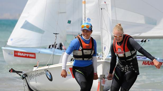 Zwei Seglerinnen schieben ihre Segelboote ins Wasser.