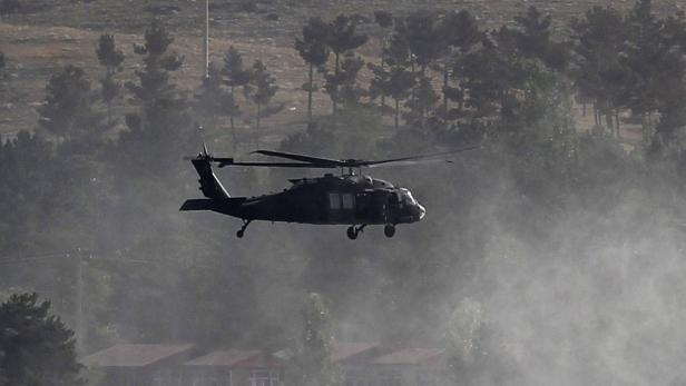 Ein Militärhubschrauber fliegt über eine bewaldete Landschaft.