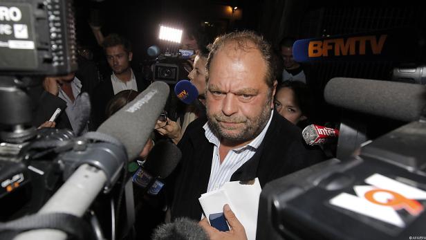 Éric Dupond-Moretti umringt von Mikrofonen und Kameras.