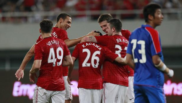 Mehrere Fußballspieler in roten Trikots umarmen sich auf dem Spielfeld.
