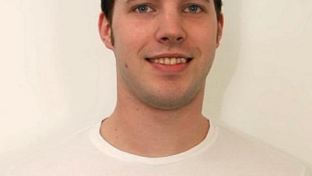 Ein junger Mann mit einem T-Shirt mit Grafikdruck lächelt in die Kamera.