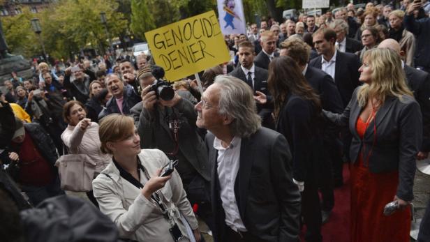 Eine Menschenmenge demonstriert mit einem Schild „Genozid-Leugner“.