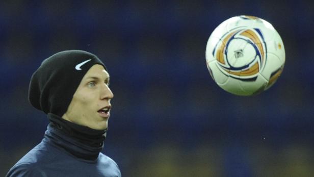 Ein Mann mit Mütze schaut auf einen Fußball.