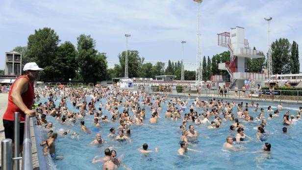 Ein Freibad ist an einem sonnigen Tag mit vielen Menschen gefüllt.