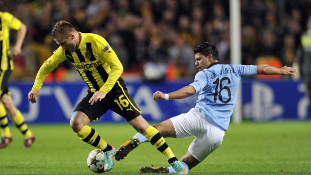Zwei Fußballspieler kämpfen um den Ball auf dem Spielfeld.