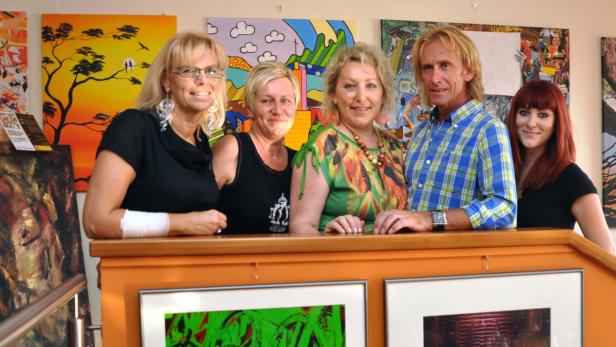 Fünf Personen stehen vor einer Wand mit Kunstwerken.