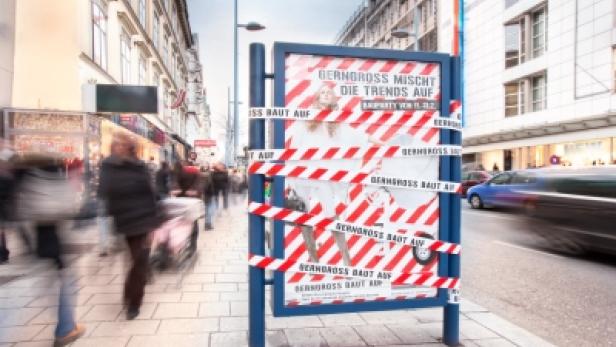 Ein Werbeplakat von Berngross ist mit rot-weißem Absperrband umwickelt.