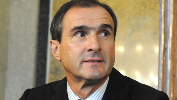 Ein Mann im Anzug blickt zur Seite.