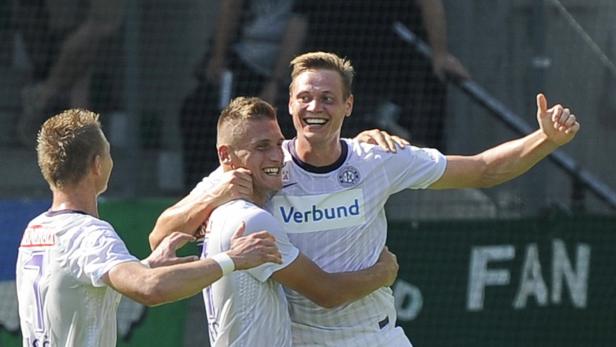 Fußballspieler feiern gemeinsam auf dem Spielfeld.