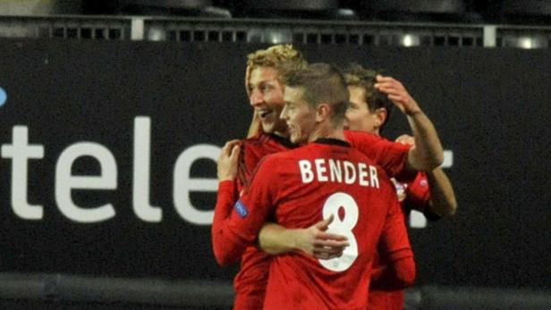 Mehrere Fußballspieler in roten Trikots umarmen sich vor einer „Telekom“-Werbung.