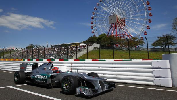 Ein Formel-1-Rennwagen auf einer Rennstrecke mit einem Riesenrad im Hintergrund.