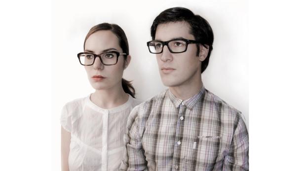 Ein Mann und eine Frau posieren mit Brillen vor einem weißen Hintergrund.