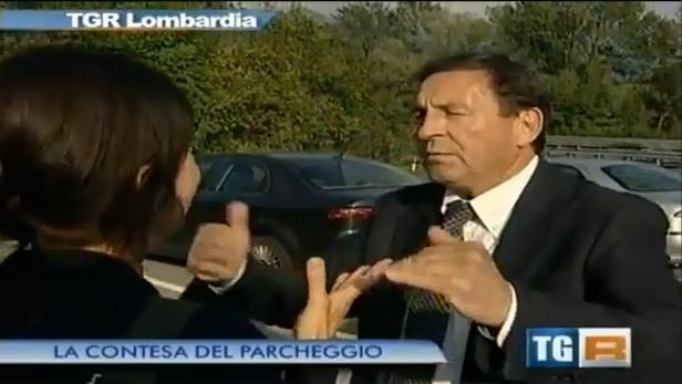 Ein Mann im Anzug gestikuliert während eines Interviews im Freien.