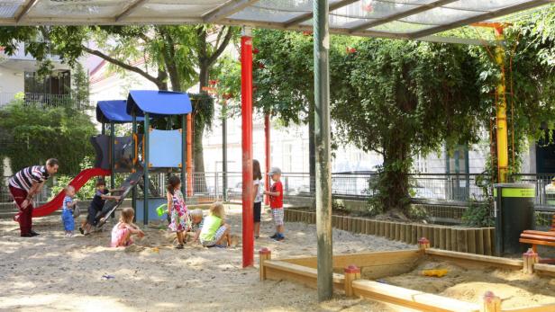 Kinder spielen in einem Sandkasten auf einem Spielplatz.