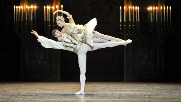 Ein Balletttänzer hält eine Ballerina in einer Hebefigur auf der Bühne.