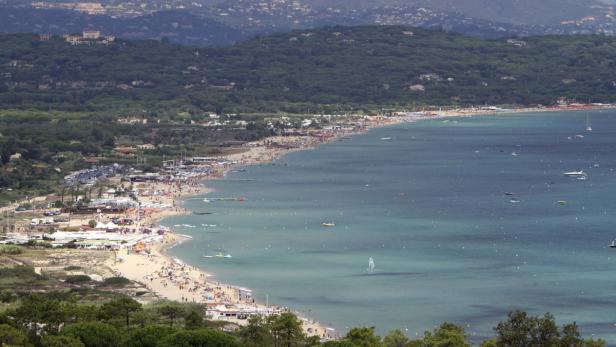 Ein Blick auf einen belebten Strand mit vielen Menschen und Booten auf dem Wasser.