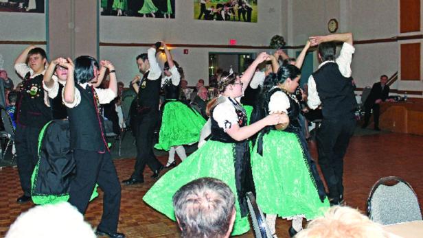 Eine Gruppe von Menschen tanzt in traditionellen deutschen Trachten.