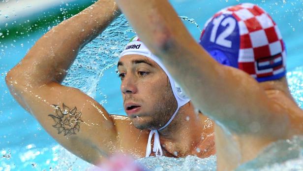 Ein Wasserballspieler mit Tätowierung am Arm im Schwimmbecken.