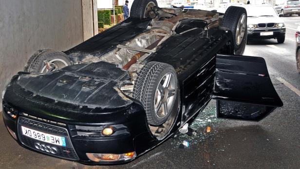 Ein schwarzer Audi liegt nach einem Unfall auf dem Dach.