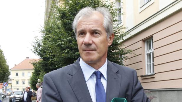 Ein Mann in Anzug und Krawatte steht vor einem Gebäude.