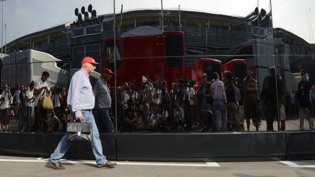 Niki Lauda geht mit einer Aktentasche an der Rennstrecke entlang.