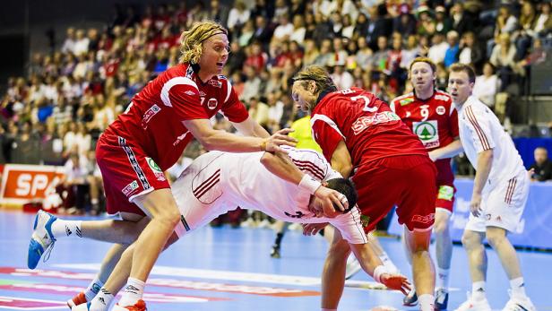 Zwei Handballspieler kämpfen um den Ball vor einer Zuschauermenge.