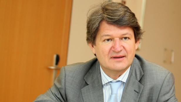 Ein Mann mit grauem Haar und Anzug blickt in die Kamera.
