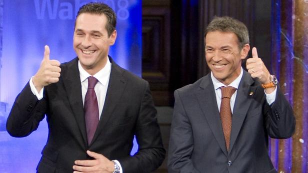 Zwei lächelnde Männer in Anzügen zeigen beide den Daumen nach oben.