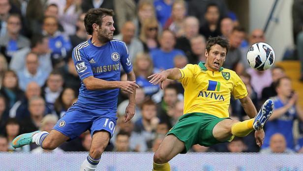 Ein Fußballspieler von Norwich City schießt den Ball, während ein Chelsea-Spieler zusieht.