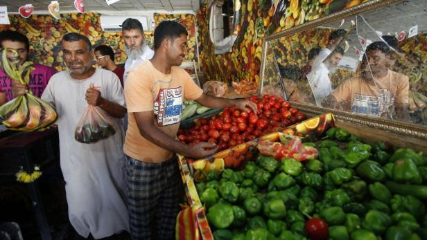 In einem Obst- und Gemüseladen kaufen Kunden Tomaten und Paprika.
