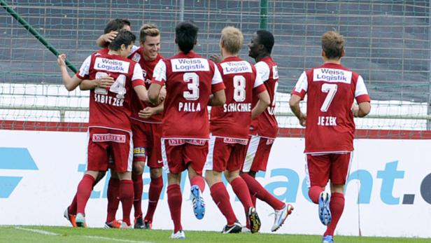 Fußballspieler in roten Trikots feiern ein Tor.