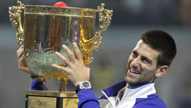 Novak Đoković hält freudestrahlend die Trophäe der China Open in den Händen.