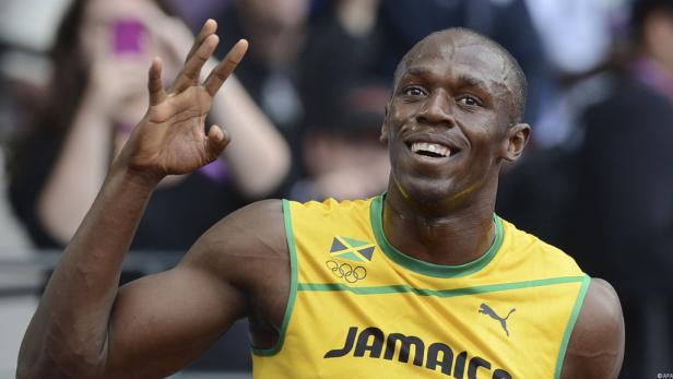 Usain Bolt lächelt und winkt in einem gelben Trikot mit der Aufschrift „Jamaica“.