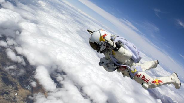 Ein Fallschirmspringer mit Red Bull-Ausrüstung springt durch die Wolken.