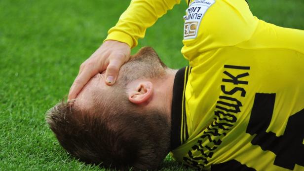 Ein Fußballspieler liegt mit schmerzverzerrtem Gesicht auf dem Rasen.