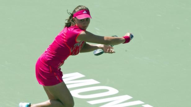 Eine Tennisspielerin in pinkfarbener Sportkleidung schlägt einen Ball.