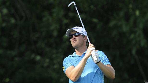 Ein Golfspieler schwingt seinen Schläger vor einem grünen Hintergrund.