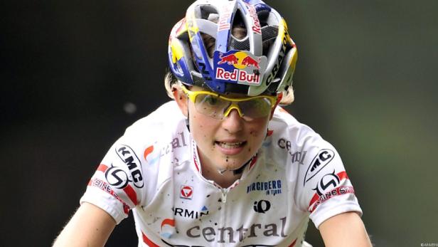Eine Mountainbikerin mit gelber Brille und Red Bull Helm während eines Rennens.