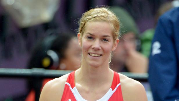 Eine blonde Frau in Sportkleidung lächelt in die Kamera.