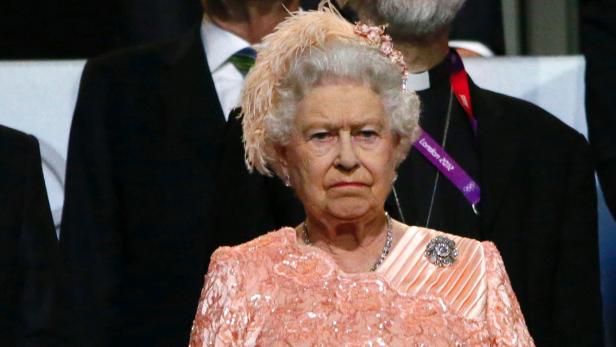 Königin Elisabeth II. trägt ein pfirsichfarbenes Kleid und einen passenden Hut.