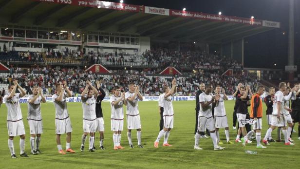 Fußballspieler applaudieren vor einem vollen Stadion.