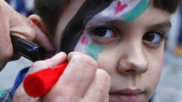 A child, member of the Syrian community in Romania, gets a Syrian flag painted on his face during a protest against the government of Syria&#039;s President Bashar al-Assad, in downtown Bucharest March 15, 2013. The protest was organized to mark two years since the start of the uprising in Syria against al-Assad&#039;s regime. REUTERS/Bogdan Cristel (ROMANIA - Tags: CIVIL UNREST POLITICS)